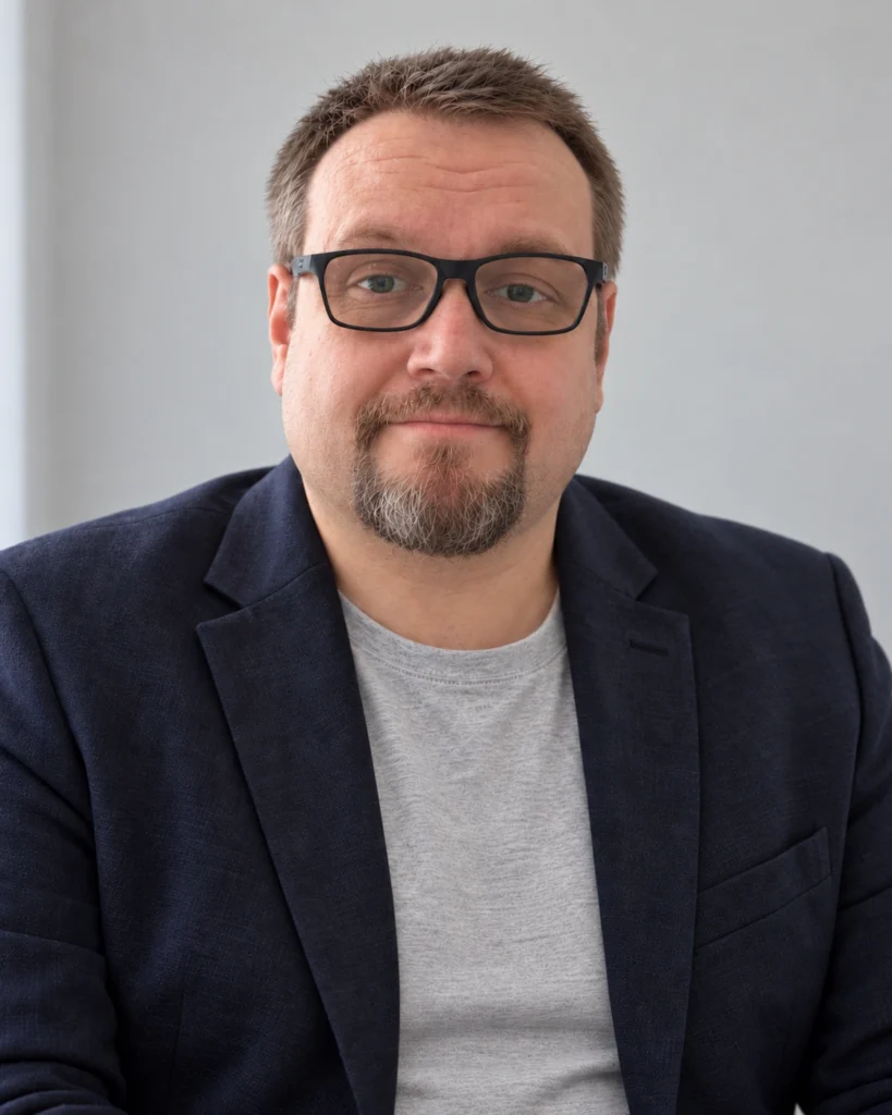Herbert Röblreiter mit sportlichem Sakko, schwarzer Brille und gepflegtem Kinnbart